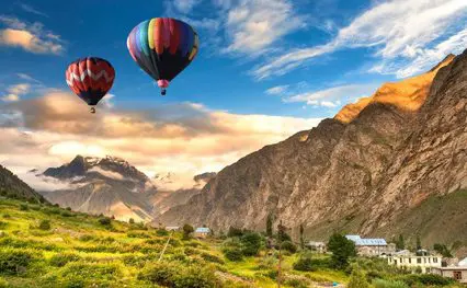 Hot air balloons flying over a village in kashmir.